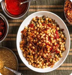 A hearty bowl of Egyptian koshary loaded with rice, lentils, pasta, chickpeas, tomato sauce and crispy onions