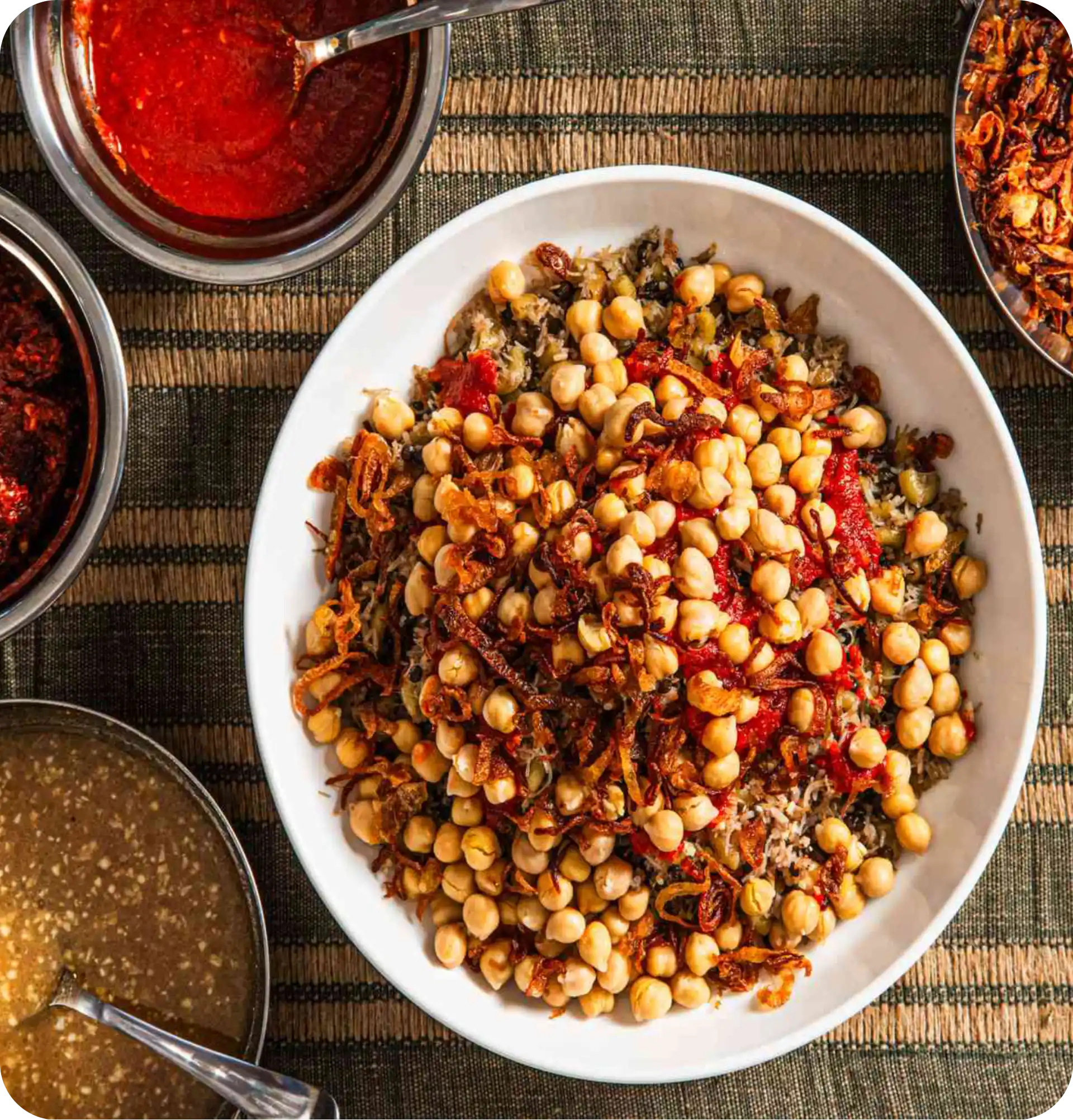 A hearty bowl of Egyptian koshary loaded with rice, lentils, pasta, chickpeas, tomato sauce and crispy onions